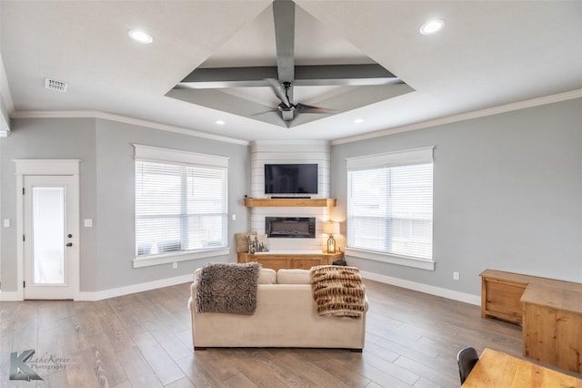 living area featuring a large fireplace, ornamental molding, a ceiling fan, and visible vents