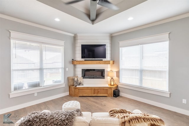 living area featuring crown molding, light wood finished floors, ceiling fan, and a healthy amount of sunlight
