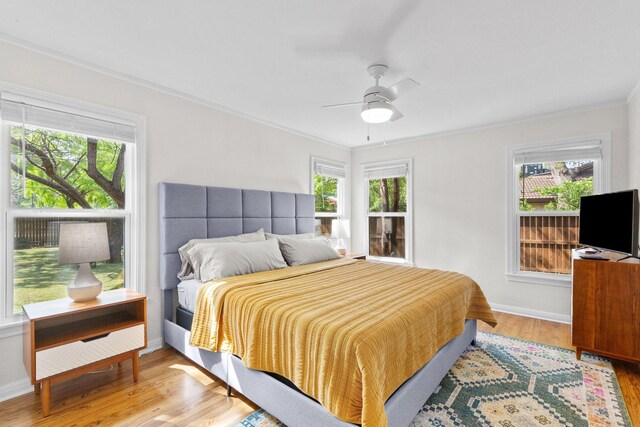 bedroom with baseboards, crown molding, wood finished floors, and multiple windows