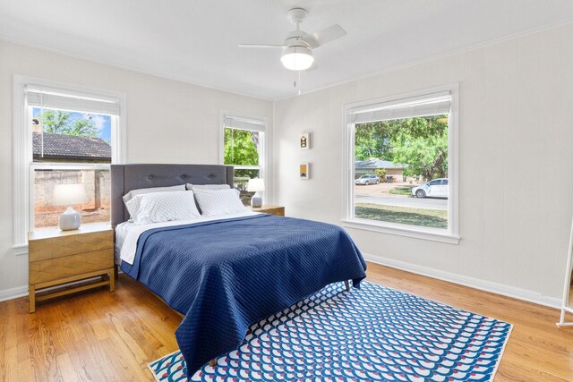 bedroom featuring baseboards, wood finished floors, and multiple windows