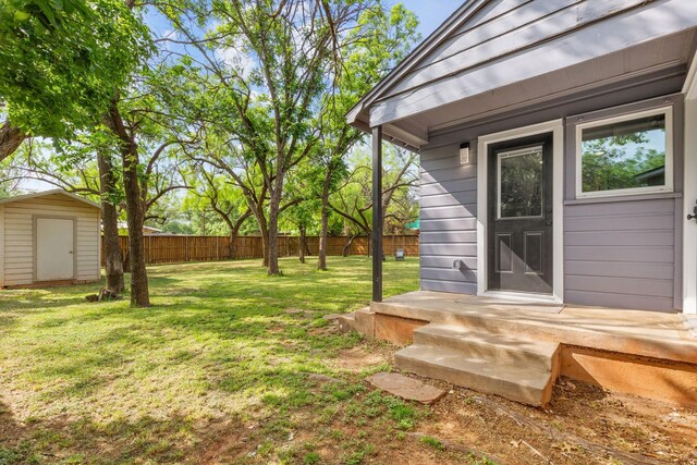 view of yard with a fenced backyard, a shed, and an outbuilding