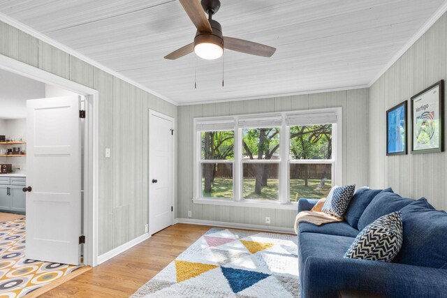 living room featuring light wood-style floors, ornamental molding, baseboards, and a ceiling fan