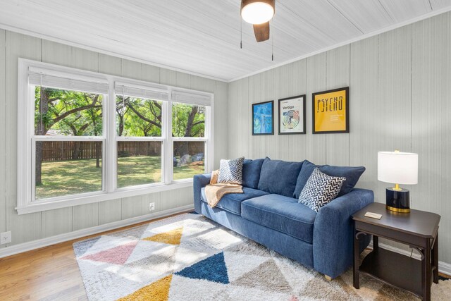 living room with crown molding, baseboards, ceiling fan, and a wealth of natural light