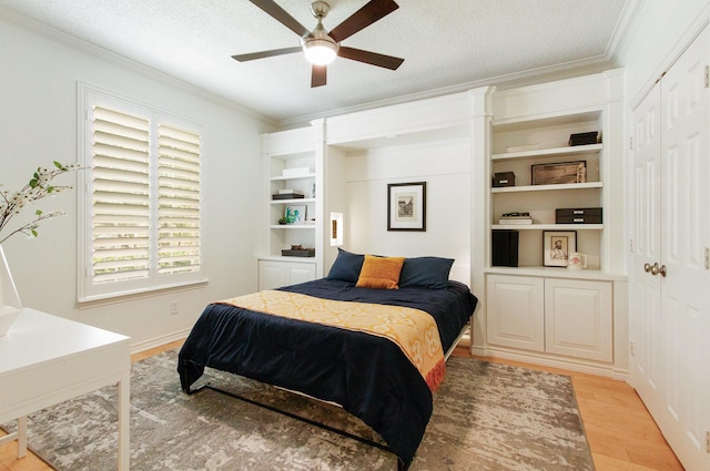 bedroom with light wood-style floors, ornamental molding, a textured ceiling, and a ceiling fan