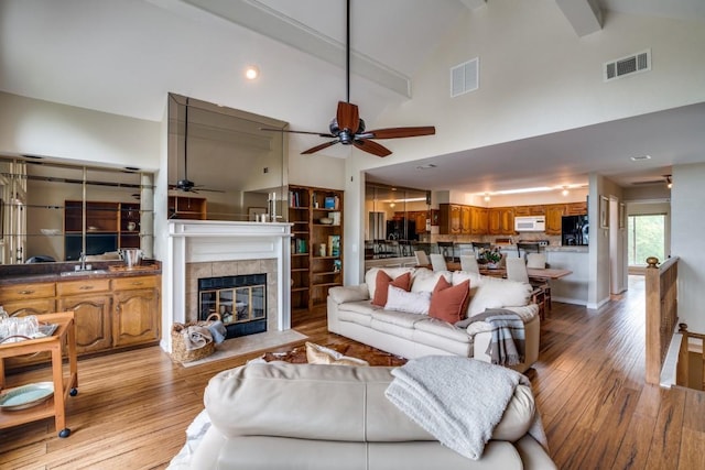 living area featuring ceiling fan, visible vents, light wood finished floors, and a fireplace