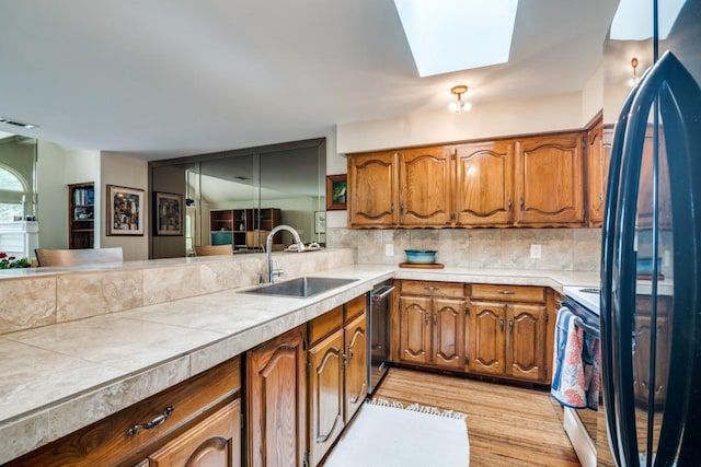 kitchen featuring brown cabinetry, range with electric stovetop, stainless steel dishwasher, a sink, and light wood finished floors