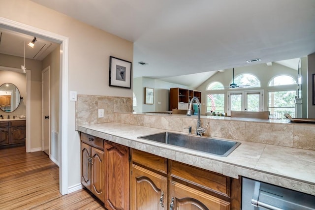 kitchen featuring a sink, light wood finished floors, lofted ceiling, and light countertops