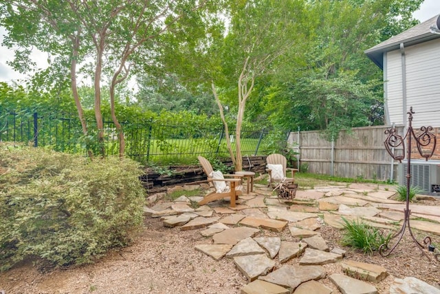view of patio / terrace with central air condition unit, a fire pit, and fence private yard