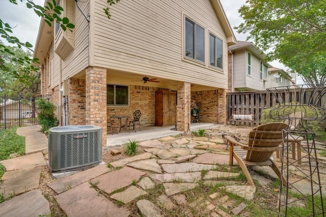 rear view of property with ceiling fan, brick siding, cooling unit, fence, and a patio