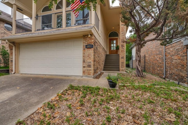 view of front of property featuring a garage, a balcony, driveway, and brick siding