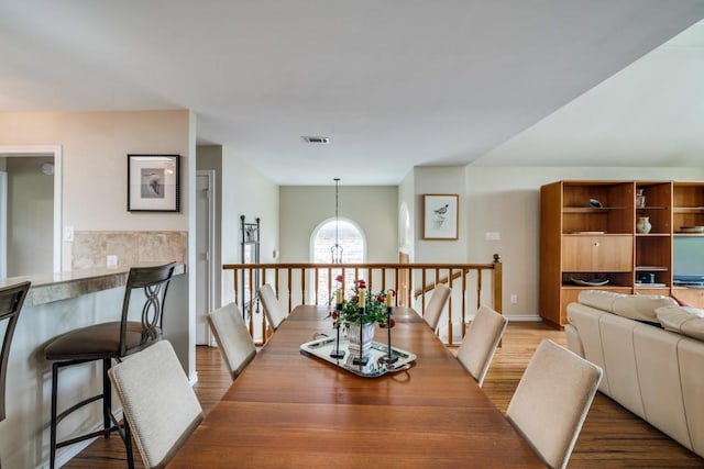 dining space featuring visible vents, wood finished floors, and a chandelier