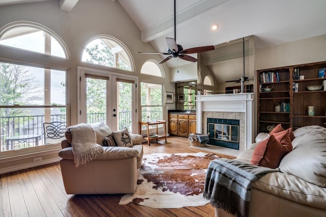 living room with beam ceiling, a fireplace, french doors, a ceiling fan, and hardwood / wood-style flooring