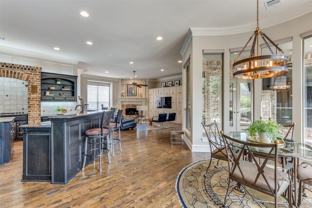 dining room with visible vents, ornamental molding, dark wood-style floors, and a fireplace