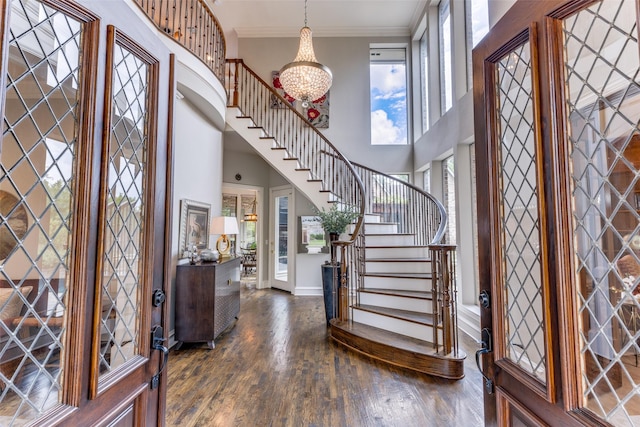 foyer with crown molding, baseboards, stairway, dark wood finished floors, and a notable chandelier