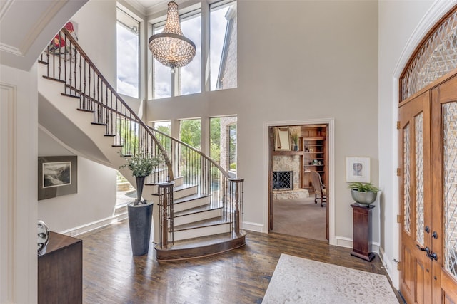 entryway featuring dark wood-style flooring, baseboards, stairway, and a towering ceiling