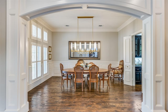 dining area featuring crown molding, arched walkways, and dark wood-type flooring