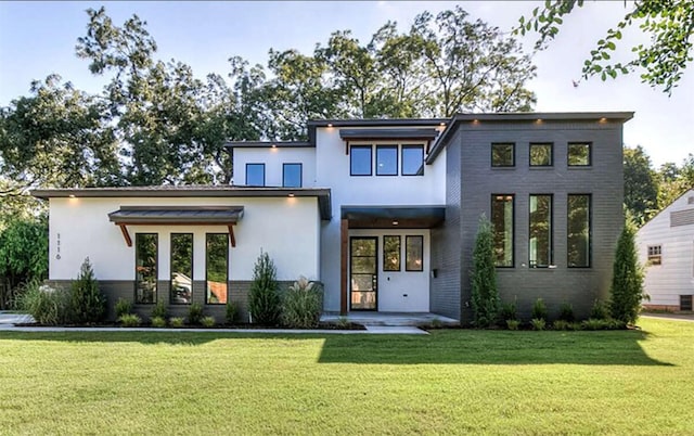 back of property featuring a yard, brick siding, and stucco siding