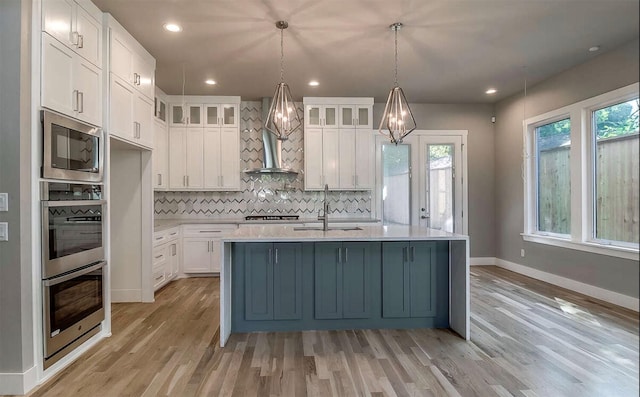 kitchen featuring stainless steel appliances, an inviting chandelier, a sink, and light wood finished floors