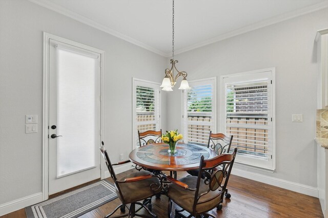 dining space with an inviting chandelier, baseboards, ornamental molding, and wood finished floors