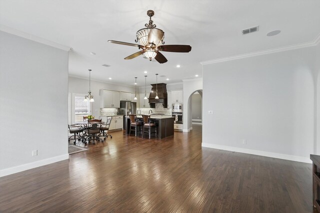 living area featuring visible vents, a ceiling fan, crown molding, dark wood-style floors, and arched walkways