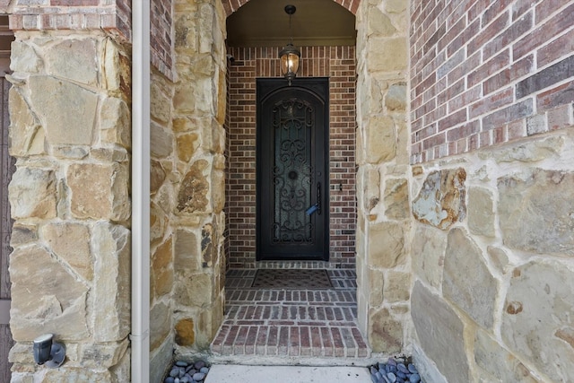 view of exterior entry featuring brick siding and stone siding