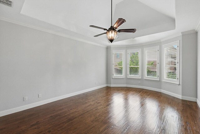 spare room featuring a ceiling fan, visible vents, wood finished floors, baseboards, and a tray ceiling