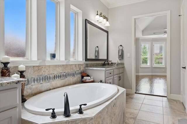 full bathroom featuring ceiling fan, a garden tub, crown molding, baseboards, and vanity