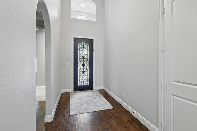 entrance foyer with baseboards, arched walkways, and dark wood finished floors