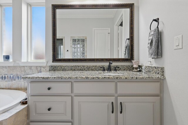 bathroom featuring vanity, ornamental molding, and a garden tub