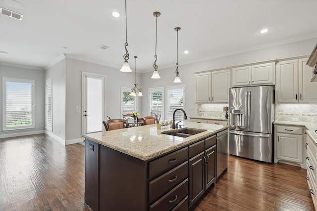 kitchen with dark brown cabinets, appliances with stainless steel finishes, a sink, decorative backsplash, and visible vents