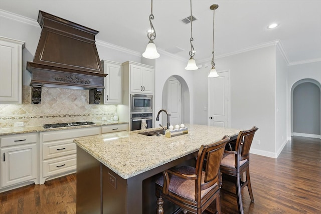 kitchen featuring appliances with stainless steel finishes, a sink, arched walkways, premium range hood, and visible vents