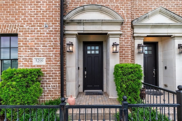 entrance to property with brick siding and fence
