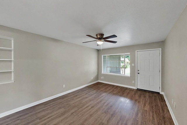 spare room with baseboards, ceiling fan, and dark wood-style floors