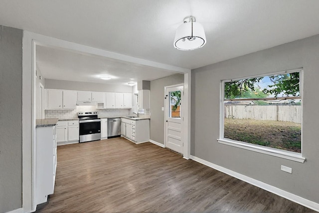 kitchen with dark wood-style flooring, appliances with stainless steel finishes, white cabinetry, baseboards, and decorative backsplash