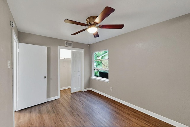 unfurnished bedroom featuring baseboards, a ceiling fan, wood finished floors, and visible vents
