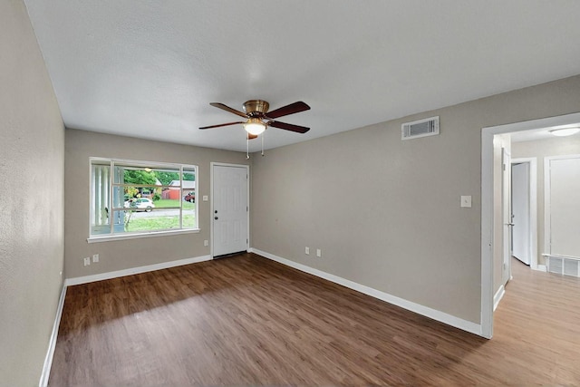 spare room featuring baseboards, ceiling fan, wood finished floors, and visible vents