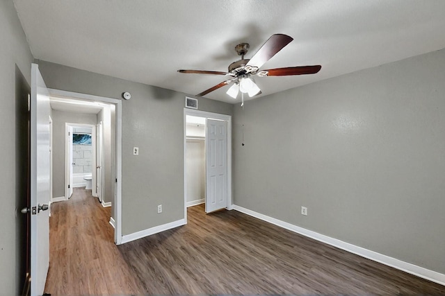 unfurnished bedroom featuring a ceiling fan, baseboards, visible vents, dark wood-style floors, and a closet