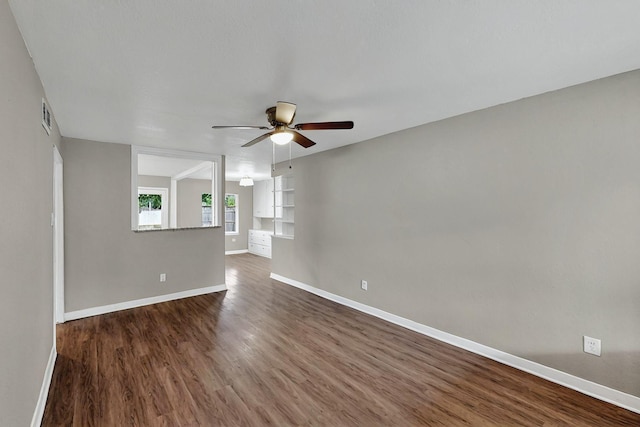 empty room featuring baseboards, ceiling fan, dark wood-style floors, and visible vents