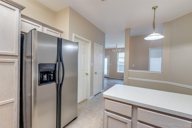 kitchen featuring stainless steel refrigerator with ice dispenser, hanging light fixtures, light countertops, light tile patterned floors, and an inviting chandelier