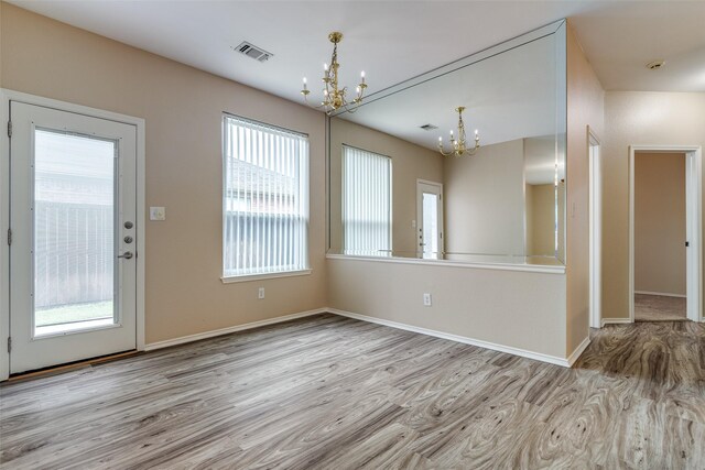 interior space featuring baseboards, an inviting chandelier, wood finished floors, and visible vents