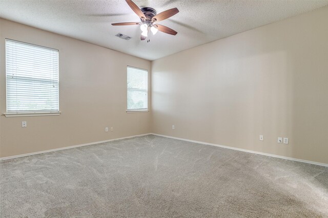 carpeted spare room featuring visible vents, a textured ceiling, baseboards, and ceiling fan