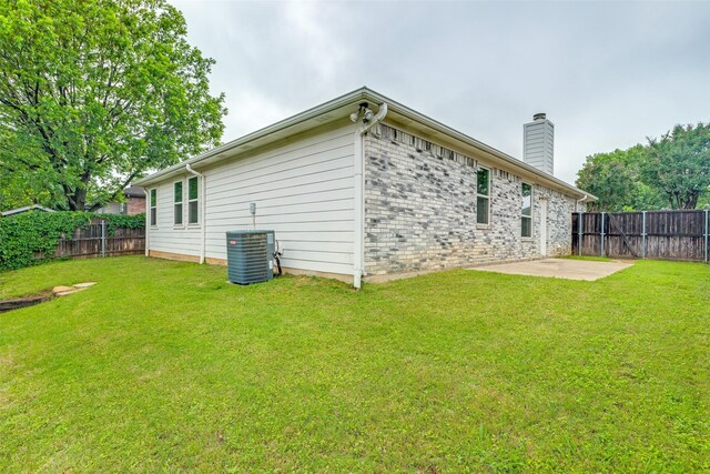 rear view of house featuring cooling unit, a patio, a fenced backyard, a chimney, and a lawn