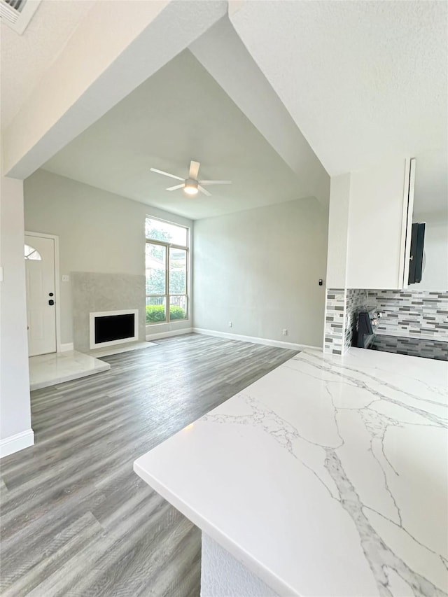 kitchen with white cabinets, baseboards, ceiling fan, and a fireplace