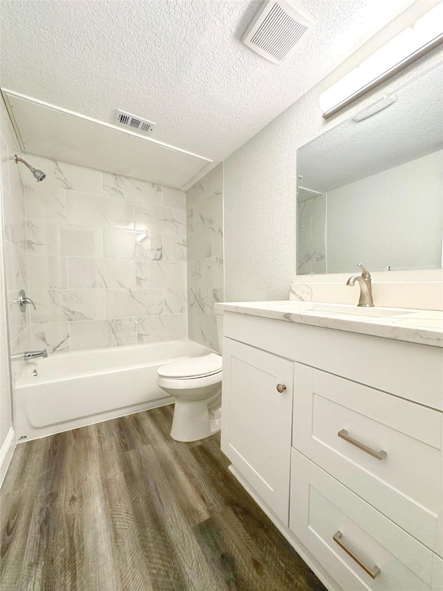 bathroom with visible vents, a textured ceiling, wood finished floors, and toilet