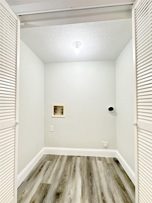clothes washing area with washer hookup, a textured ceiling, laundry area, and wood finished floors