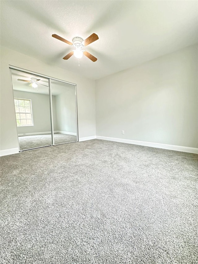 unfurnished bedroom featuring carpet floors, baseboards, a ceiling fan, and a closet