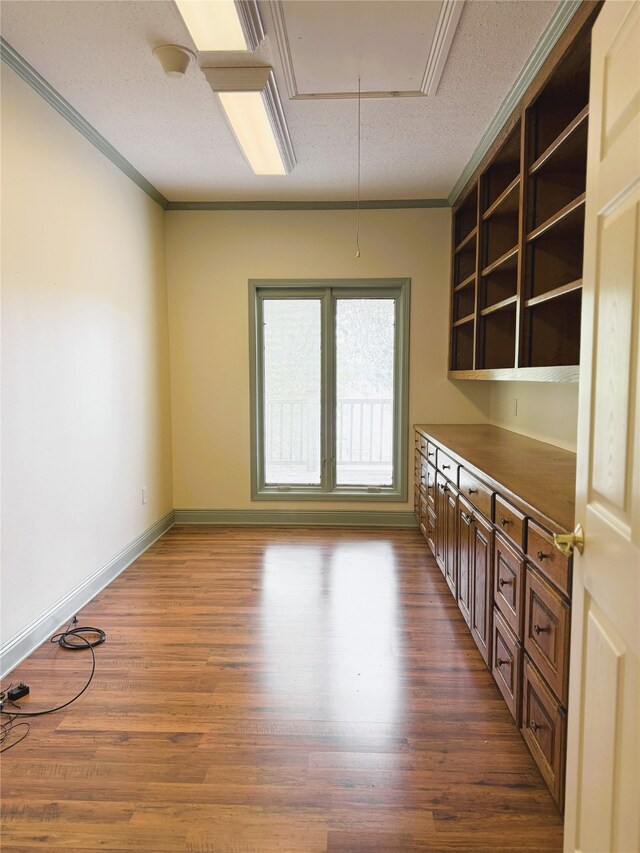 spare room featuring ornamental molding, baseboards, attic access, a textured ceiling, and dark wood finished floors