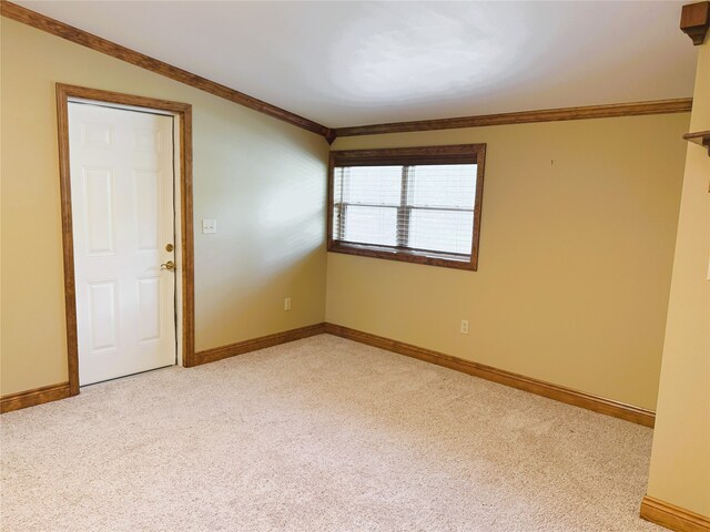 spare room with light colored carpet, ornamental molding, and baseboards