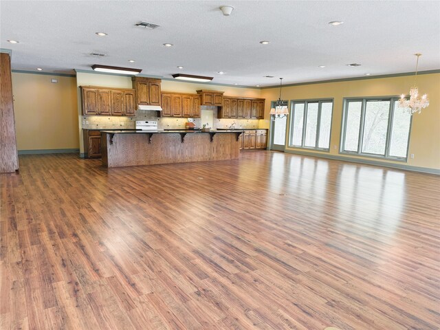 unfurnished living room featuring baseboards, a notable chandelier, wood finished floors, and visible vents