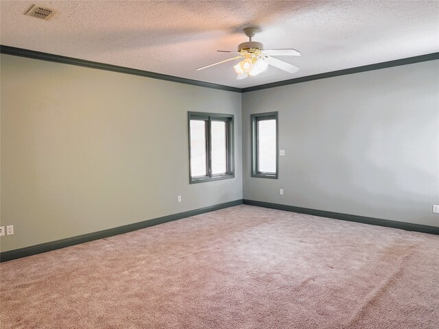 spare room featuring a ceiling fan, a textured ceiling, visible vents, crown molding, and carpet